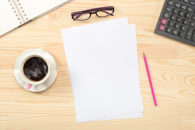 Notepad, coffee cup, green potted plant, office supplies on wooden table. Flat lay