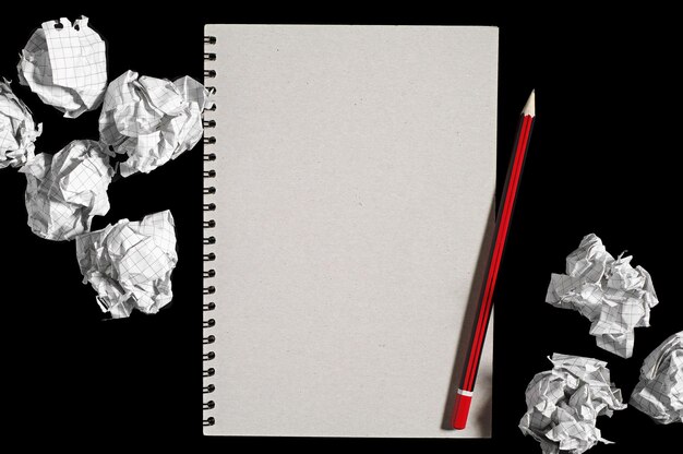 Notepad and crumpled paper balls on black background. Conceptual photo