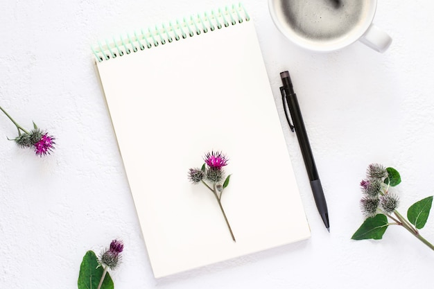 Notepad, cup of coffee and pencil on white background, flat lay.