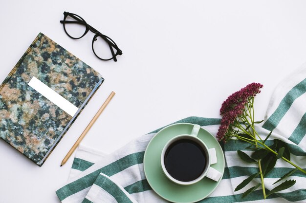 Notepad and cup of coffee on white.