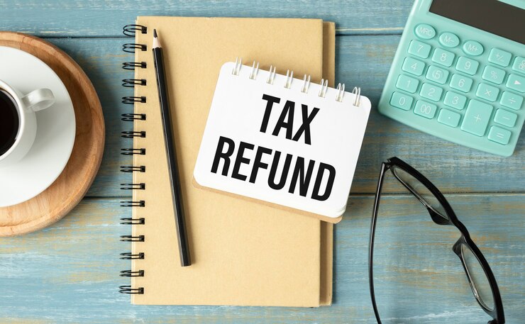 Photo notepad, flower vase, spectacle, storage card, pencil, magnifying glass and words tax refund on wooden paper