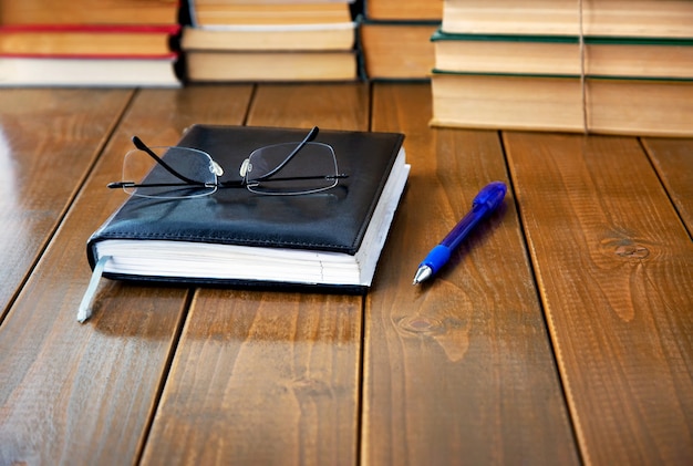 Notepad glasses pen and books on the table Closeup