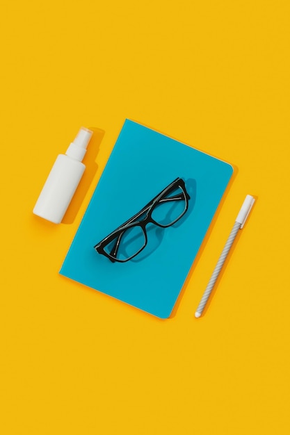 Notepad glasses pen and sanitizer against an orange background