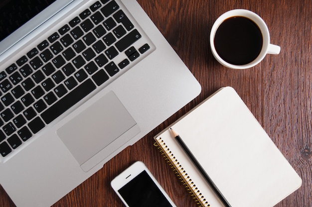 notepad, laptop and coffee cup on wood table