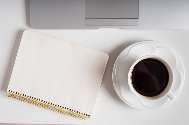 Notepad, laptop and coffee cup on wood table