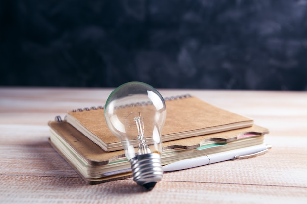 Notepad and light bulb on the table. concept writing ideas