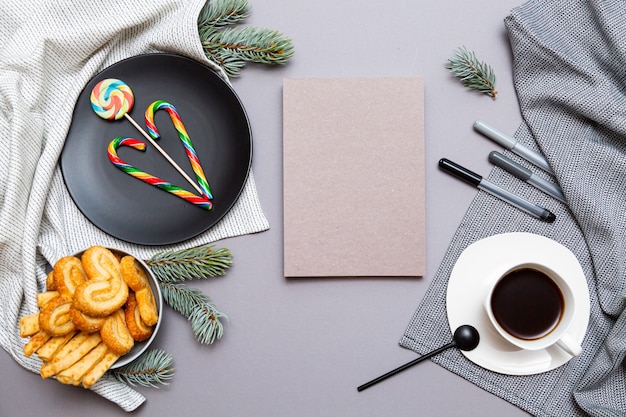 Notepad, lollipops, cookies, fir branches and a cup of coffee