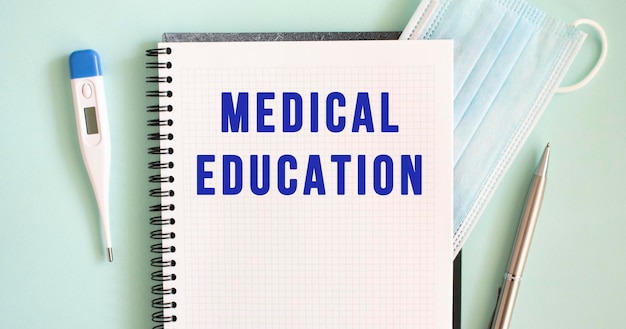 Blocco note maschera medica termometro e penna su sfondo blu educazione medica testo in un quaderno