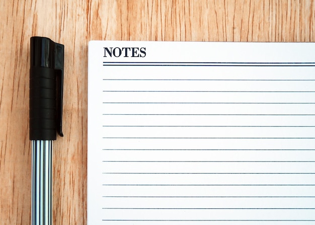 Photo a notepad and pen are on a wooden table.