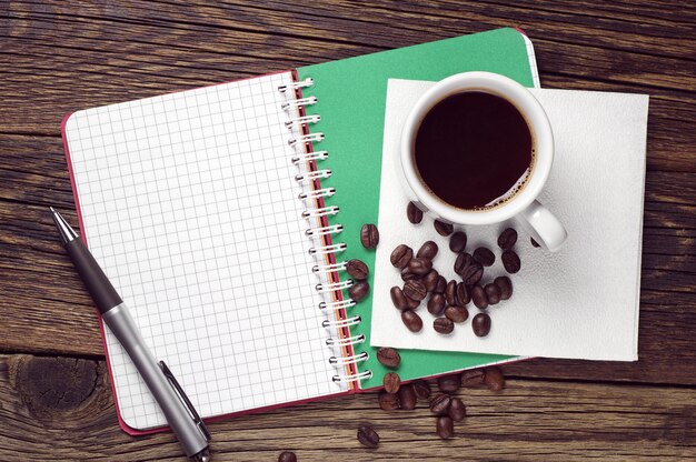 Notepad, pen and coffee cup on dark wooden table, top view