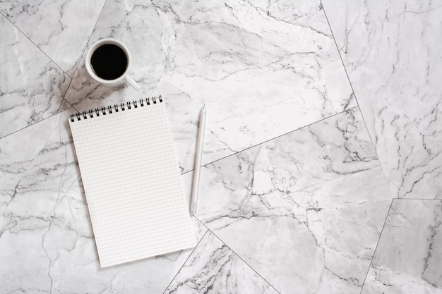 Notepad pen and cup of black coffee on marble tiles Planning and reminder