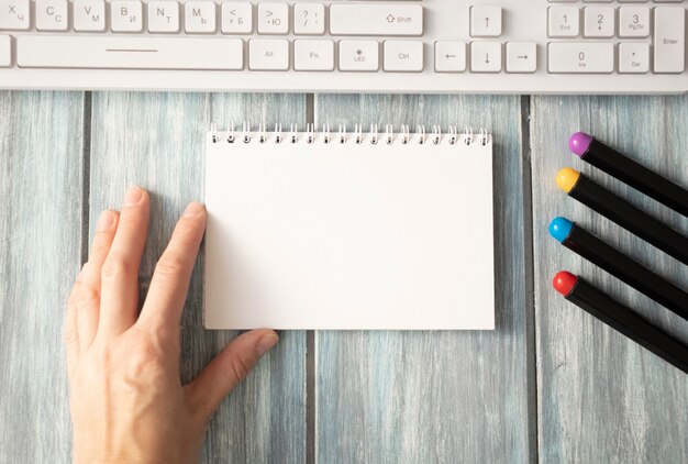 Photo notepad, pen, hand, keyboard on wooden table