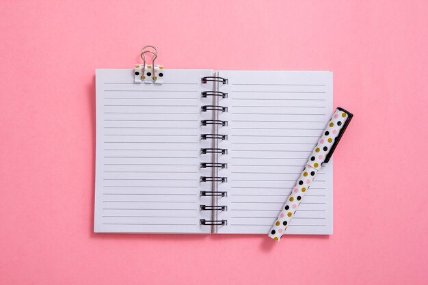 Notepad and pen on pink background