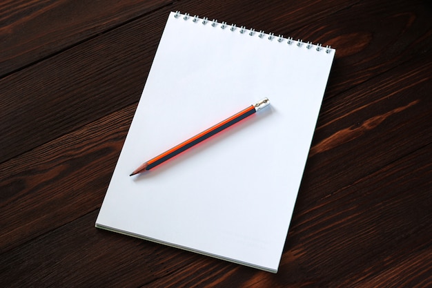 Notepad and pencil on wooden background