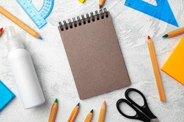 Notepad, stationery and hand sanitizer top view on desk