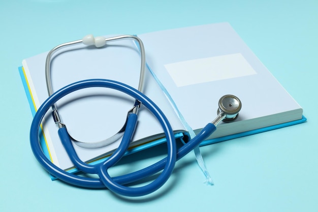 Notepad and stethoscope on blue background close up