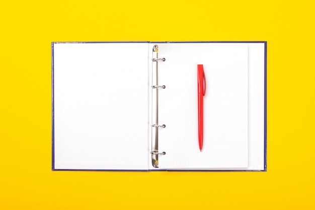 Фото Блокнот с шариковой ручкой на желтом фоне