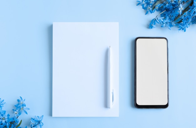 Notepad with blank white sheets on a blue background with plant elements top view