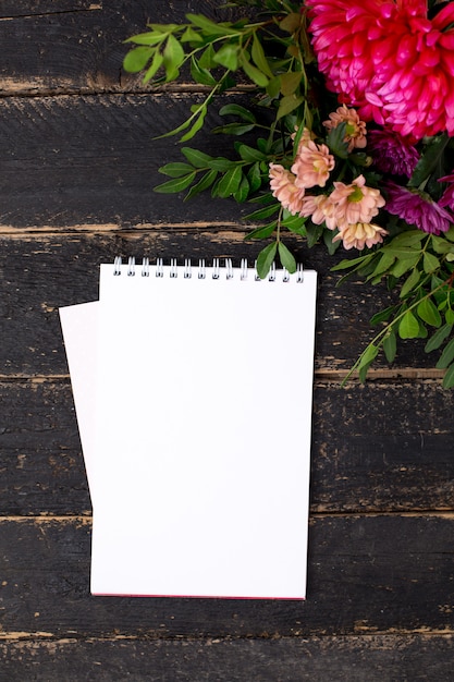 Notepad with a bouquet of flowers on a dark vintage wood