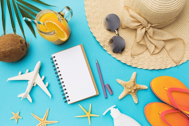 Notepad with copy space for text next to a toy plane and various accessories for relaxation on a blue background