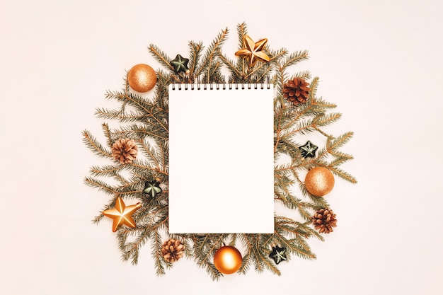 Notepad with holiday decorations in green and golden colors on white background, copyspace. Christmas and New Year planning flatlay concept.