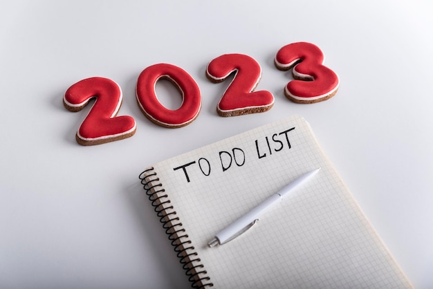 白い背景に TO DO LIST ペンと数字 2023 が刻まれたメモ帳 クローズ アップ 2023 年の計画と目標