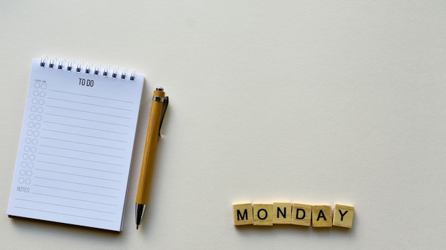 写真 ペンと木製の単語「月曜日」のメモ帳