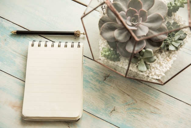 Notepad with pen and flower on the table