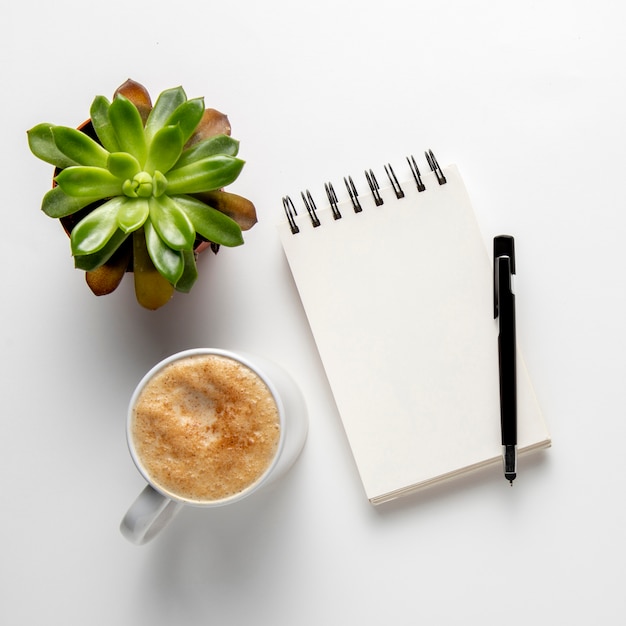 Notepad with pen near coffee mug