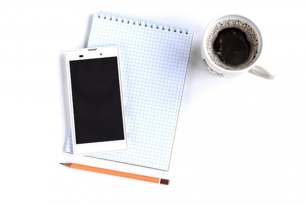 スマートフォン、鉛筆、コピースペース付きの白いテーブルにコーヒーとメモ帳。フラットレイ。