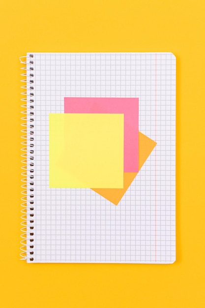 A notepad with sticky notes on yellow table