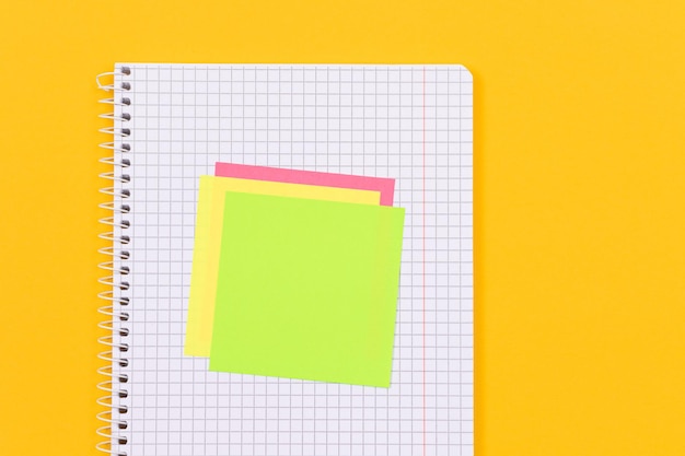 A notepad with sticky notes on yellow table