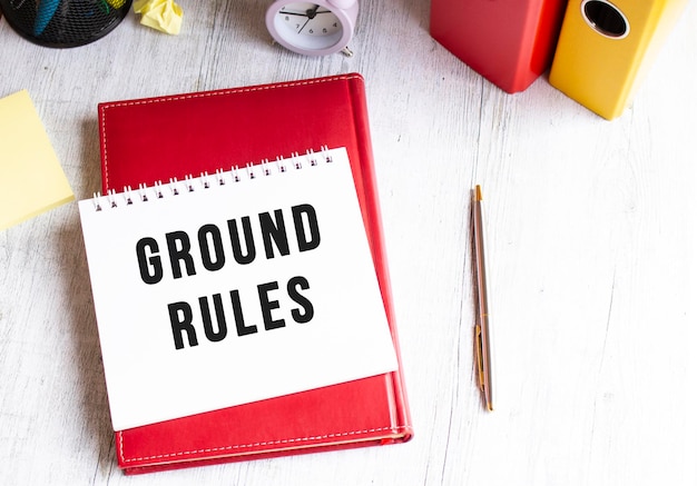 木製のテーブルに「GROUND RULES」というテキストが書かれたメモ帳赤い日記とペン