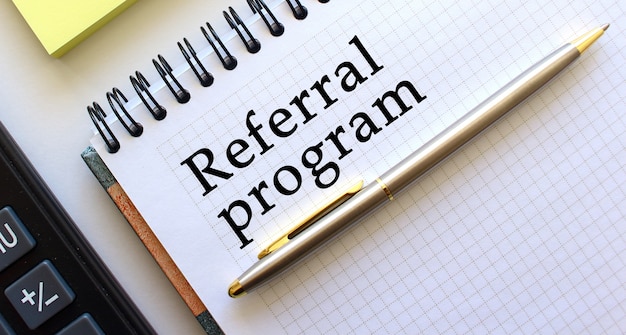 REFERRAL PROGRAM 텍스트가있는 메모장. 비즈니스 개념.