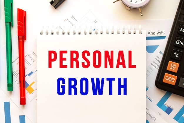 컬러 금융 차트에 텍스트 Personal Growth가있는 메모장. 펜, 사무실 테이블에 계산기.