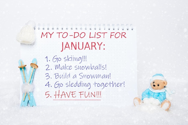 Notepad with a todo list skiing making snowballs making a snowman sledding having fun and a toy Teddy bear