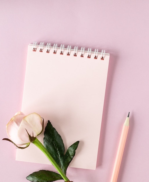 Notepad for your text on a light pink surface with pink roses