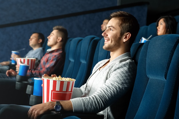 Nothing better than a good movie. Cheerful casual man spending time watching movie with snacks at the local movie theater