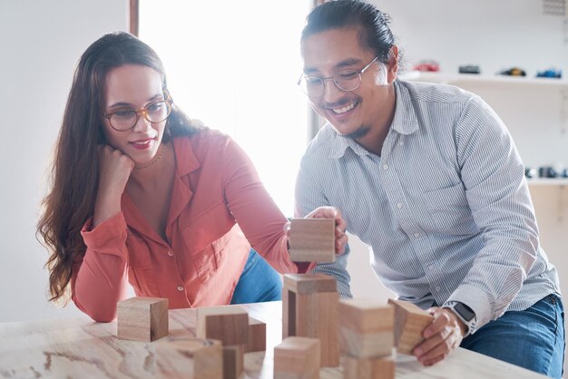 Photo nothing drives change like innovation shot of a young businessman and businesswoman having a meeting with building blocks in a modern office