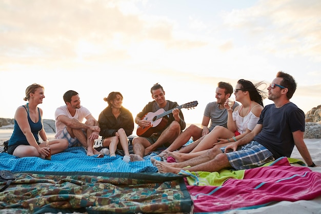 Nient'altro che buone vibrazioni sulla spiaggia oggi foto di un gruppo di giovani amici felici che si godono insieme un picnic sulla spiaggia