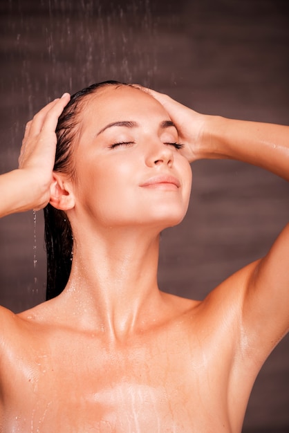 暖かいシャワーのようなものはありません。シャワーで立って髪を洗う美しい若い上半身裸の女性