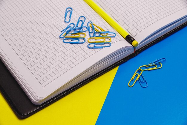 notitieblok met wit geblokte vellen, paperclip. klem. potlood. briefpapier.