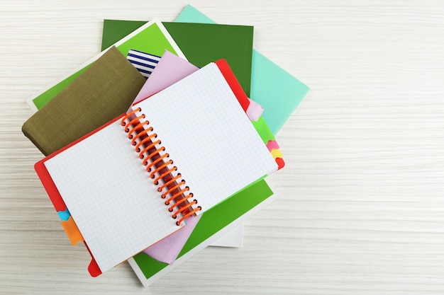 Notitieboekje bovenop stapel boeken en tijdschriften op houten achtergrond