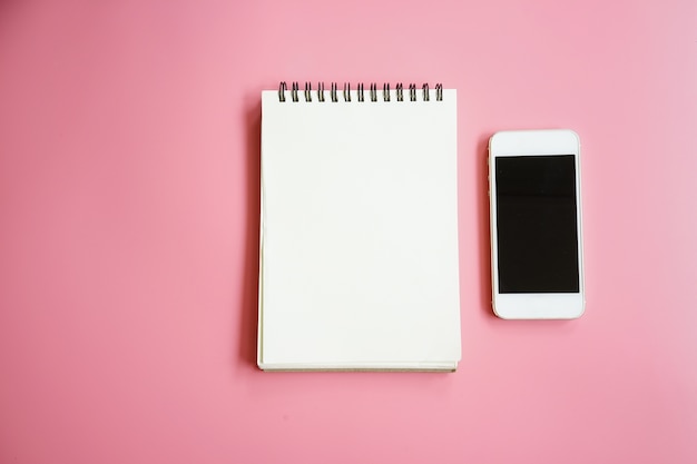 notitieboekje en smartphone op roze achtergrond
