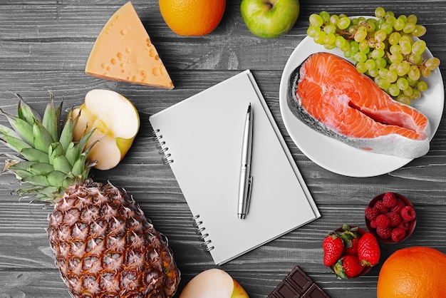 Notitieboekje met pen en gezonde voeding op blauwe houten tafel