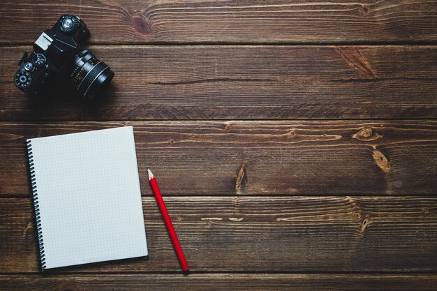 Notitieboekje met rode pen en vintage camera op oud houten bureau Bovenaanzicht Vrije ruimte voor ontwerp