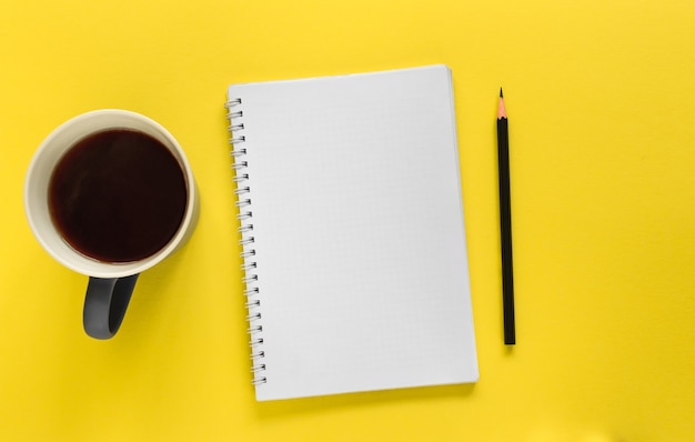 Notitieboekje, potlood en mok koffie (thee) op de gele achtergrond. Te doen lijst
