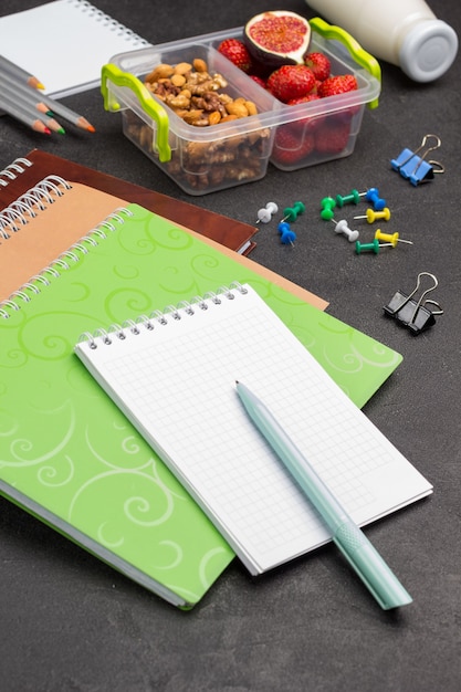 Foto notitieboekjes en pen met schooldoos met fruit en noten