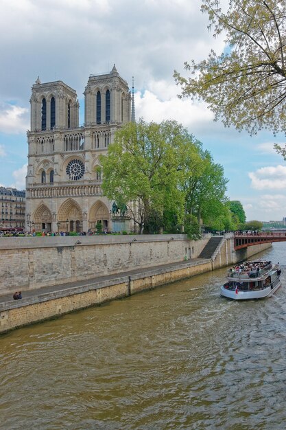 Notre Dame de Paris-kathedraal, rivierboot en oever van de Seine in Parijs, Frankrijk. Of Kathedraal van Onze-Lieve-Vrouw van Parijs in het Engels. Mensen op de achtergrond