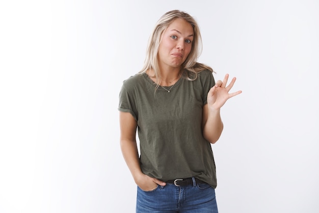 Nou niet slecht. Portret van een schattige jonge vrouw die een onhandige man probeert te ondersteunen, een verrassingsdiner op Valentijnsdag maakt, lippen tuitend maakt en zich een onzekere grimas maakt en een goed gebaar laat zien, oké